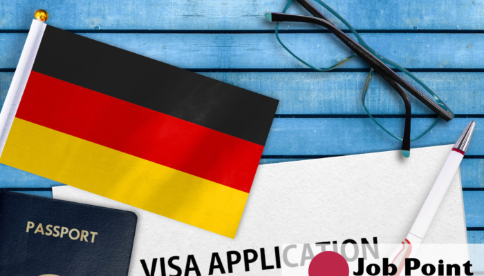 niemiecka flaga, paszport, okulary i długopis, logo w prawym dolnym rogu